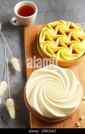 Delicious mini tarts yellow and white with nuts and custard on wooden cutting board. Assortment of delicious and colorful dessert, lemon curd tart, cr Stock Photo