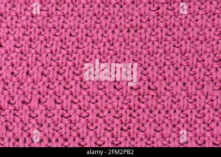 Pink knitted fabric pearl woolen background. The structure of the fabric with a natural texture. Fabric background. Knitted woolen background. Stock Photo