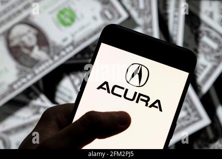 In this photo illustration the Japanese luxury automobile brand owned by automaker Honda, Acura, logo seen displayed on a smartphone with USD (United States dollar) currency in the background. Stock Photo