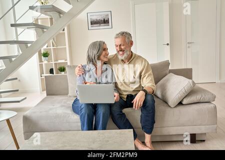 Happy senior mature family couple using laptop computer at home. Stock Photo