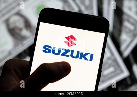 In this photo illustration the Japanese multinational automobile manufacturer Suzuki logo seen displayed on a smartphone with USD (United States dollar) currency in the background. (Photo by Budrul Chukrut / SOPA Images/Sipa USA) Stock Photo