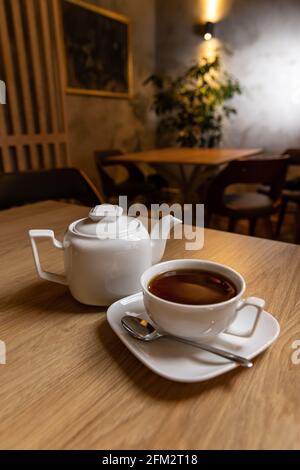 White porcelain tea cup and teapot, Afternoon tea table setting in restaurant Stock Photo
