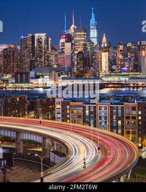 Traffic and light trails on 'The Helix', a highway loop at the entrance in Lincoln Tunnel. The New York skyline shines in the background. Stock Photo