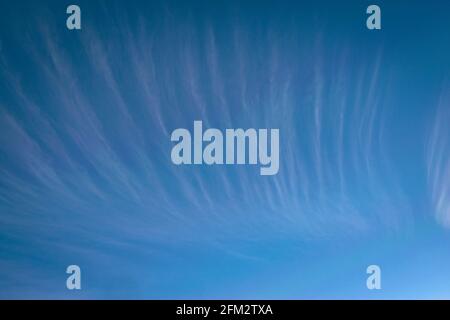 High altitude cirrus clouds in the form of stripes against blue sky as background Stock Photo