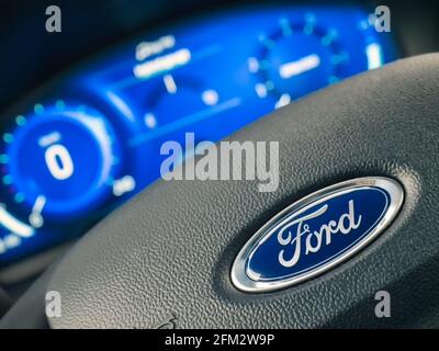 Galati, Romania - September 05, 2020: Focus on Ford logo on steering wheel, out of focus of the dashboard, speedometer and tachometer. Modern car inte Stock Photo
