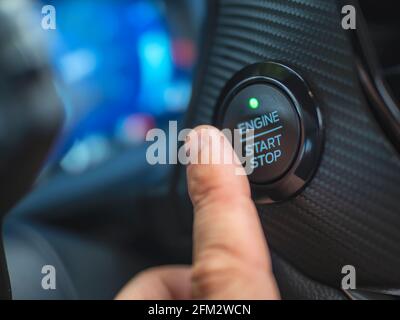 The driver's finger is pressing the car start button. Concept of transportation and technology Stock Photo