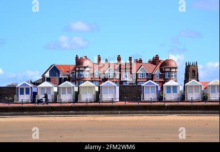 Sand in front of a row of beach huts in the sunshine at St Annes On Sea, Fylde, Lancashire, England. Stock Photo