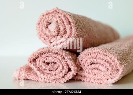 pastel pink bath towel rolls on shelf, selective focus Stock Photo