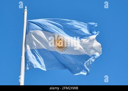 Argentine flag flying on a flagpole against a blue sky on a sunny day. Patriotic symbol of Argentina Stock Photo