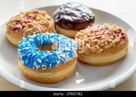 Donuts with different toppings on white plate. Stock Photo