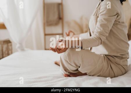 Cropped image of African-American woman practicing yoga and relaxation exercises on bed. Stock Photo
