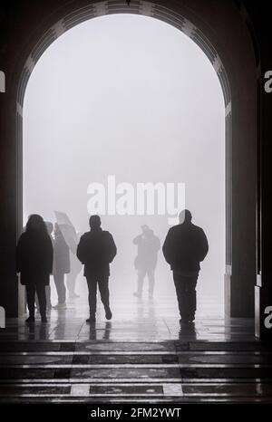 Domestic and International tourists wearing facemarks are visiting the monastery of Montserrat during a misty and rainy spring day, at the end of the pandemic induced Spanish State of Emergency in the Montserrat mountain range, west of Barcelona in the province of Catalonia, Spain. © Olli Geibel Stock Photo