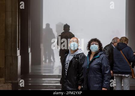 Domestic and International tourists wearing facemarks are visiting the monastery of Montserrat during a misty and rainy spring day, at the end of the pandemic induced Spanish State of Emergency in the Montserrat mountain range, west of Barcelona in the province of Catalonia, Spain. © Olli Geibel Stock Photo