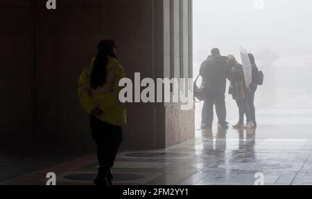 Domestic and International tourists wearing facemarks are visiting the monastery of Montserrat during a misty and rainy spring day, at the end of the pandemic induced Spanish State of Emergency in the Montserrat mountain range, west of Barcelona in the province of Catalonia, Spain. © Olli Geibel Stock Photo