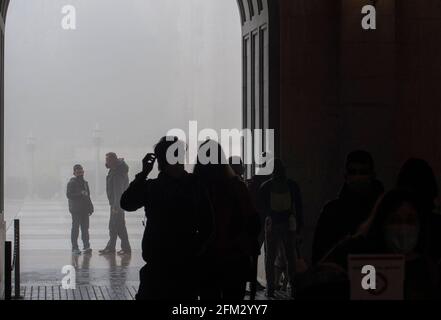 Domestic and International tourists wearing facemarks are visiting the monastery of Montserrat during a misty and rainy spring day, at the end of the pandemic induced Spanish State of Emergency in the Montserrat mountain range, west of Barcelona in the province of Catalonia, Spain. © Olli Geibel Stock Photo