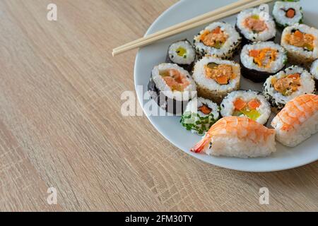 Closeup on sushi set of maki with chopsticks on a white plate Stock Photo
