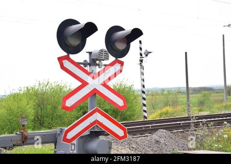 Railway level crossing with semaphore and barrier. Warning road sign on the proximity of a railway crossing. Stock Photo