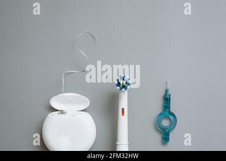 Electric toothbrush, floss and interdental brushes on a gray background. Flat lay, copyspace. Stock Photo