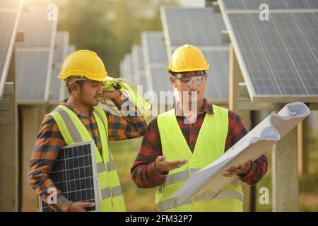 Two engineers looking at construction plans at a solar powered station, Thailand Stock Photo