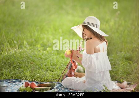 Woman sitting on a picnic blanket peeling an apple, Thailand Stock Photo