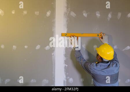 Construction worker using a spirit level on a building site, Thailand Stock Photo