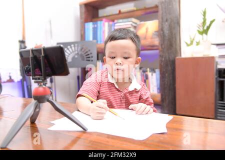 Boy sitting at home doing an online video class Stock Photo