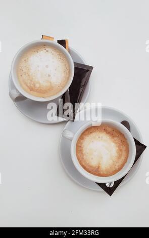 Overhead view of two cups of coffee on a table with sachets of sugar Stock Photo