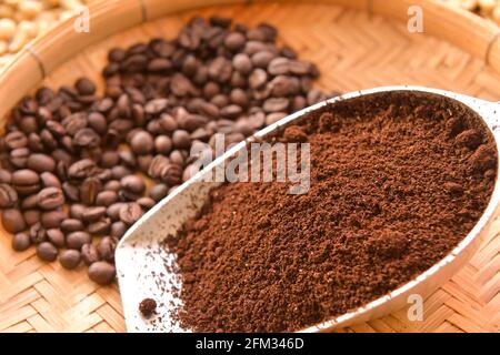 Roasted coffee beans and ground coffee on a bamboo tray Stock Photo