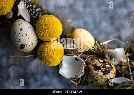 Close-Up of an Easter wreath decorated with quail eggs and feathers on a table Stock Photo