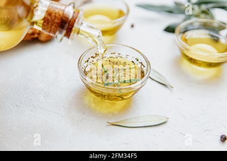 Olive oil being poured into a pot with rosemary and oregano Stock Photo