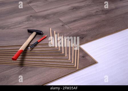 Hammer and pencil on laminate panels, carpenter tools for laying laminate in the room. Stock Photo