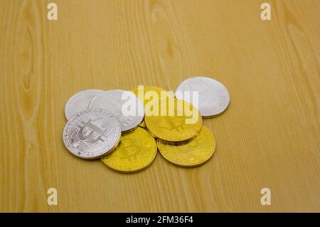 Closeup of a pile of white and gold bitcoin coins on top of a wooden table with copy space Stock Photo