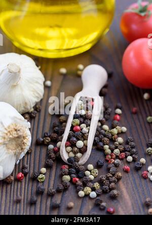 Close-up of mixed peppercorns on a table with garlic, tomatoes and olive oil Stock Photo