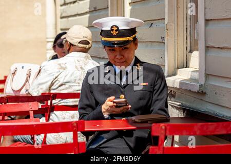 Annapolis, MD, USA 05-02-2021: A young Asian American female cadet training at the US Naval Academy in Annapolis is sitting at a restaurant table with Stock Photo