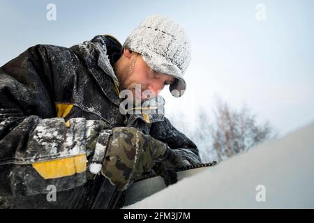 A manual file worker sharpens a chainsaw chain Stock Photo