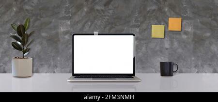 Mock up laptop computer with blank white screen of placed on office white table Stock Photo