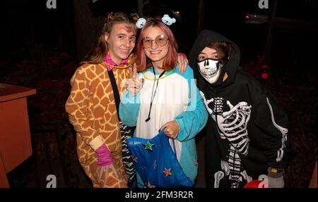 Halloween trick and treat teenage girls costumed as giraffe, outer space creature, and skeleton.  St Paul Minnesota MN USA Stock Photo
