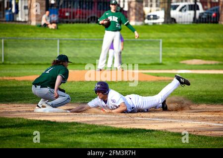 High school baseball game at Cretin Durham Hall with player sliding headfirst into third base. St Paul Minnesota MN USA Stock Photo