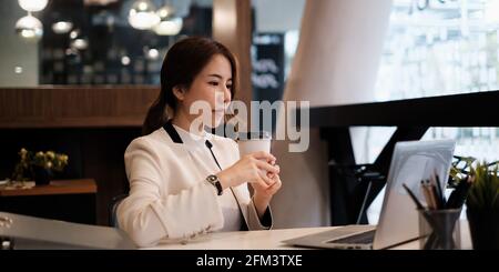 Female executive thinking over working schedule for employee writing report into digital laptop in coworking space. Stock Photo