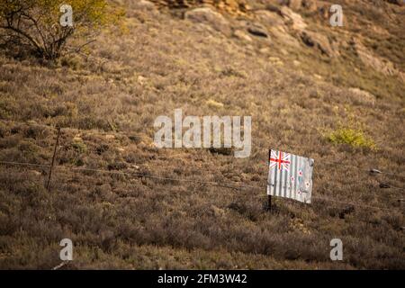 New Zealand Flag painted on Corrugated Iron Hanging on a Wire Fence in Rugged Farmland, Central Otago, South Island, New Zealand Stock Photo