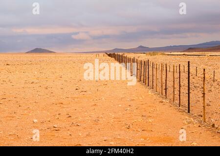 empty desert landscape with fence by cloudy day in Namibia Stock Photo