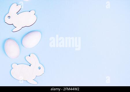 Top view flat lay funny wooden Easter Bunny with eggs as symbols of a holiday with copy space on light pink background. Stock Photo
