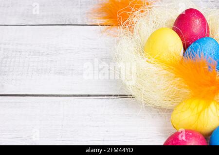 Colorful painted Easter eggs decorations in the nest with copy space on light wooden background. Stock Photo