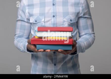 Dark skinned mans hands holding textbooks Stock Photo
