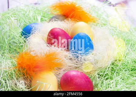 Colorful painted Easter eggs decorations in the nest on light green background. Stock Photo