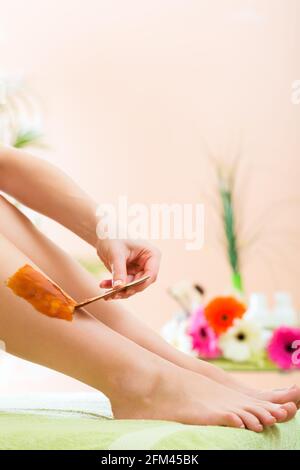 Young woman in Spa getting legs waxed for hair removal Stock Photo