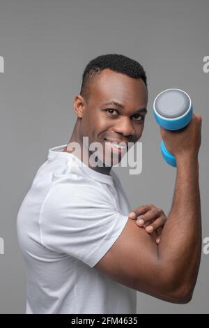 Happy man with dumbbell showing biceps Stock Photo