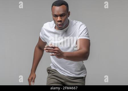Energetic young dark skinned man running Stock Photo