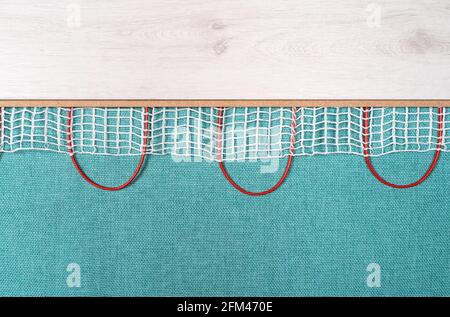 Heated floor under laminate background. Underfloor electric heating. Warm floor system texture. Mat electric floor heating system. Stock Photo