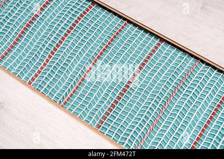 Heated floor under laminate background. Underfloor electric heating. Warm floor system texture. Mat electric floor heating system. Stock Photo